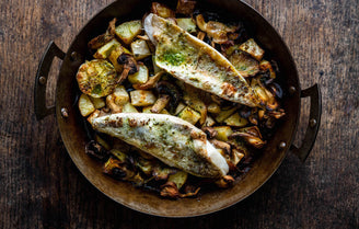 Sustainably caught cooked gurnard fish with parsley butter on bed of potatoes wild mushrooms in pan 