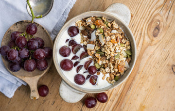 riverford natural fat free yogurt in a bowl with grapes and granola with a bunch of grapes on a table