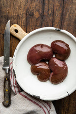 A plate showcasing four raw Native Breed Pig's kidneys